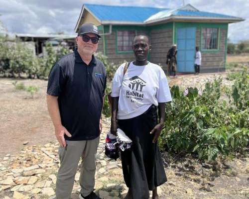 A man and a woman standing in front of a home. 